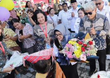 Wali Kota Pematangsiantar yang juga Bunda Pendidikan Anak Usia Dini (PAUD) Kota Pematangsiantar dr Susanti Dewayani SpA didampingi Ketua TP PKK H Kusma Erizal Ginting SH disambut seorang balita yang menyerahkan krans bunga saat menghadiri Pelepasan Siswa-siswi PAUD Sanggar Anak Balita (SAB) yang dikelola Tim Penggerak (TP) PKK se-Kota Pematangsiantar yang digelar di Lapangan Adam Malik. ( Nawasenanews/ Ist)