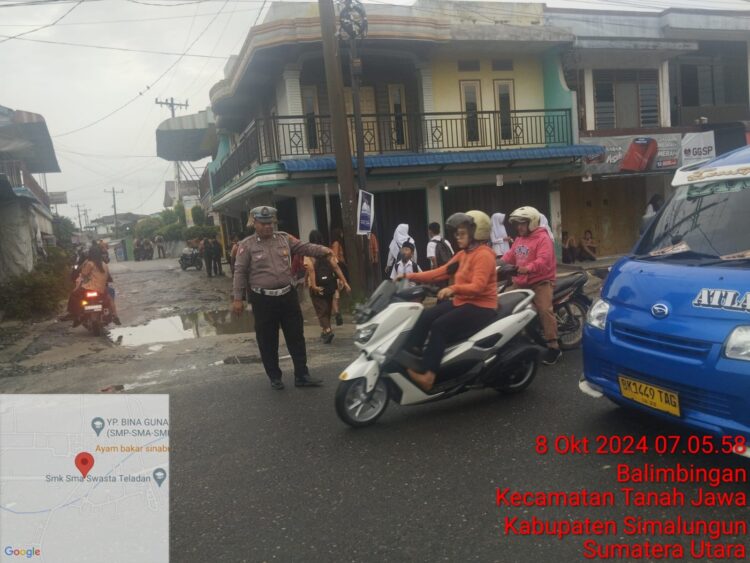 Polsek Tanah Jawa saat mengatur lalu lintas yang dipimpin Bripka H Siahaan berlangsung di tengah gerimis dengan fokus pada pengaturan dan pengamanan lalu lintas di Simpang Tangsi, Nagori Balimbingan, Kecamatan Tanah Jawa, Kabupaten Simalungun,Selasa (08/10/2024). (Nawasenanews/ Ist)