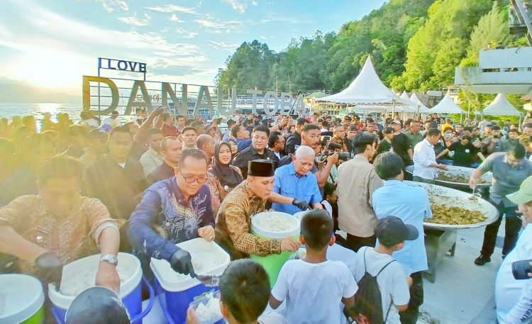 Wakil Bupati Simalungun (Baju batik coklat) membagikan nasi dengan lauk ayam rica- rica kepada pengunjung pada acara makan besar atau Mangan Baggal dalam rangka memperingati HUT ke- 77 di Ruang Terbuka Publik ( RTP) Pantai Bebas Parapat.(Ist/ Mar/Nawasenanews)