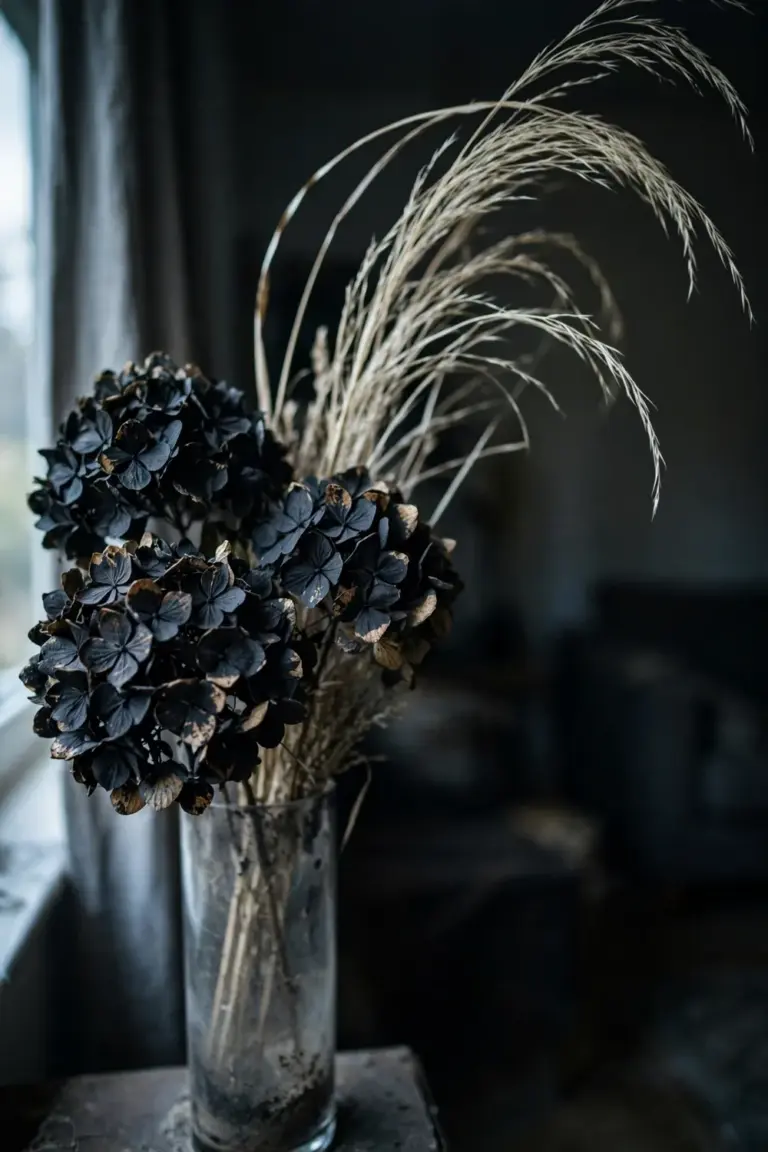 Dried hydrangea heads sprayed matte black in a tall vase with dried grasses