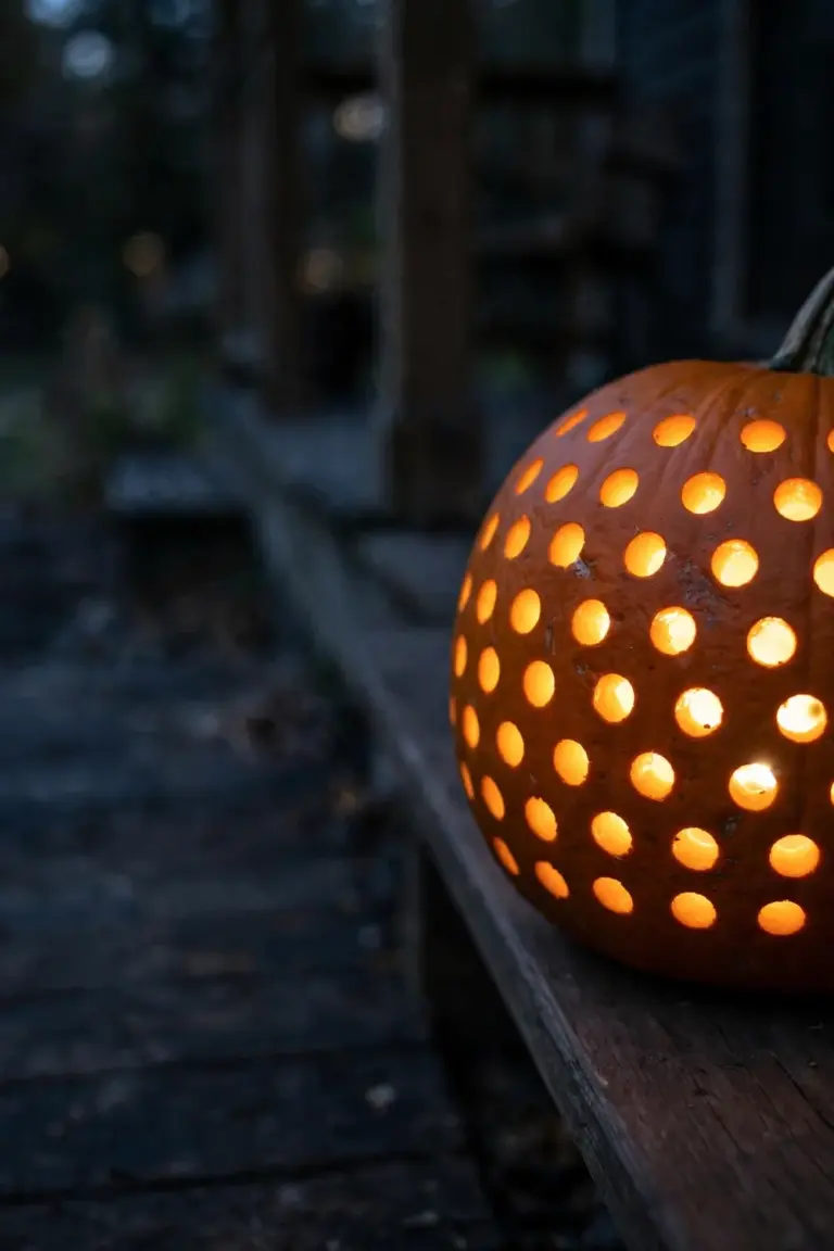 Pumpkin covered in neat rows of drilled round holes glowing as points of light at dusk