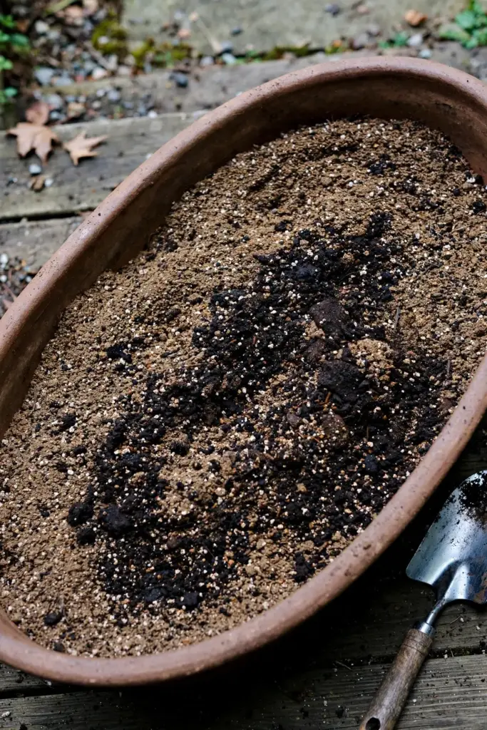 Potting mix being blended with dark compost in a large container