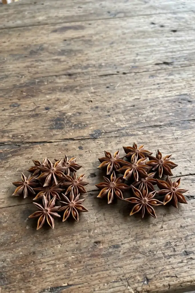 Two small piles of dried star anise pods compared side by side on a wooden table
