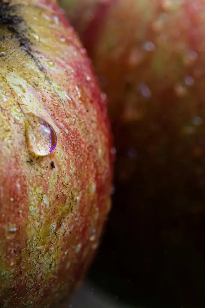 Apple skin macro with water beading on the waxy surface.