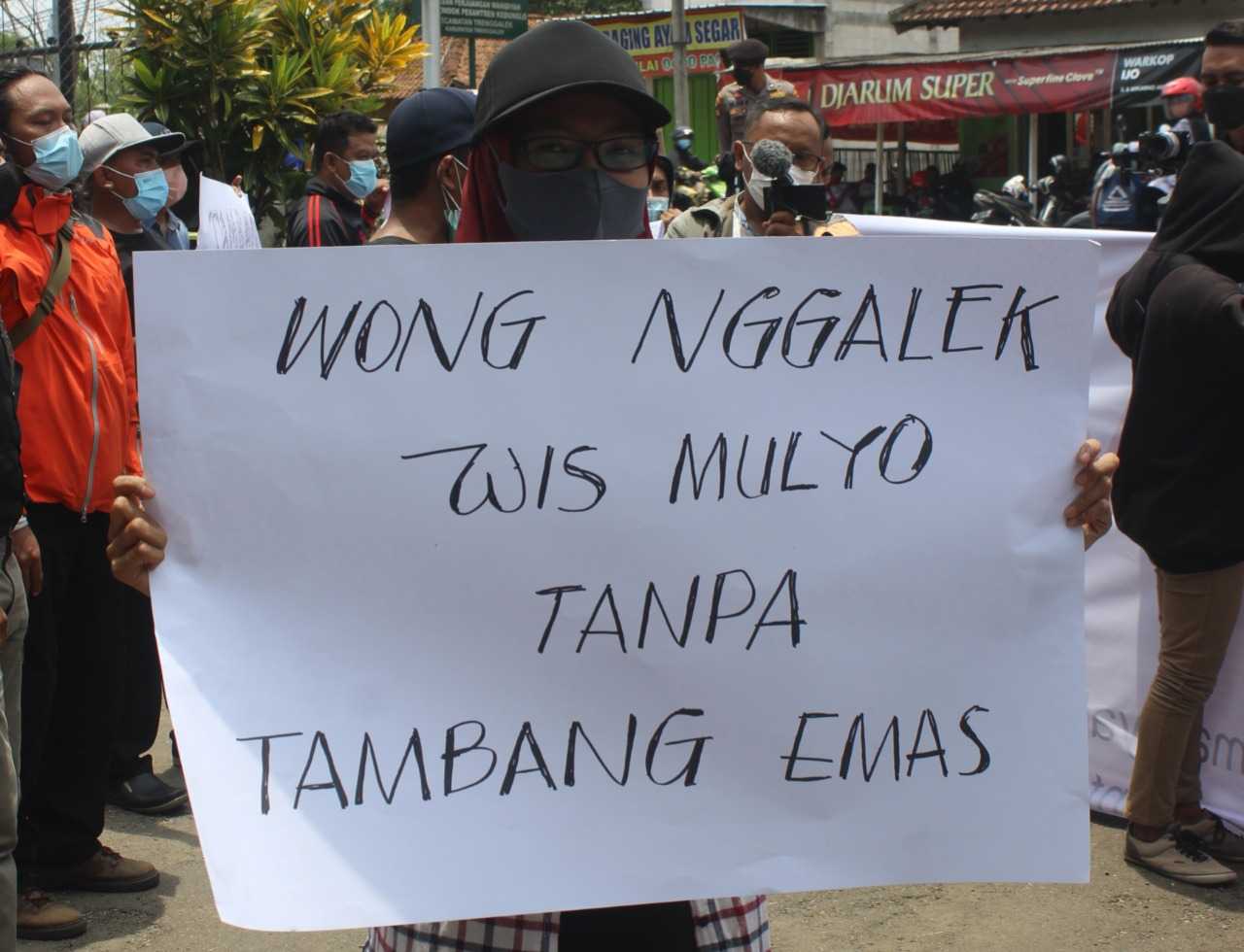 Salah satu massa aksi Aliansi Rakyat Trenggalek membentangkan poster tolak tambang emas di Trenggalek