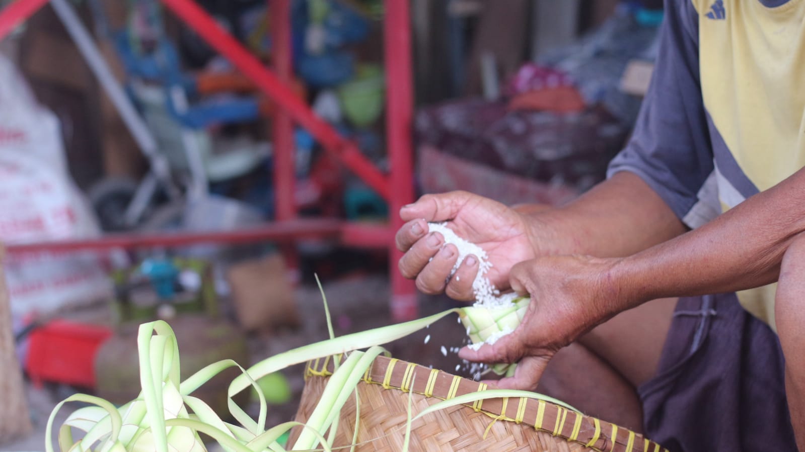 Proses memasukkan beras ke dalam wadah ketupat