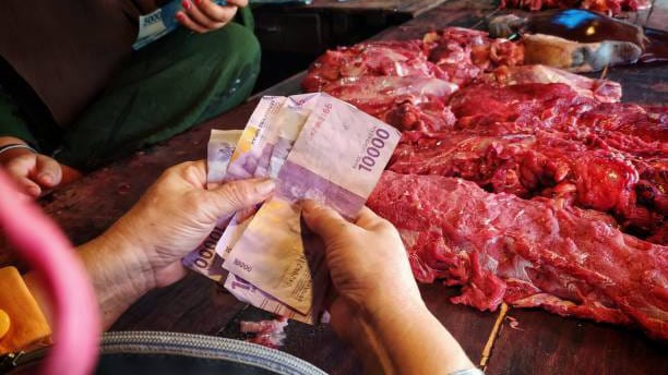Pedagang menghitung uang hasil jualan daging sapi