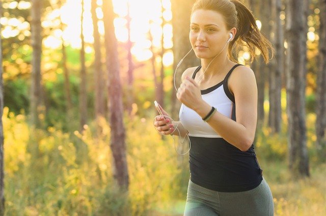 Seorang perempuan sedang olahraga lari lari di hutan