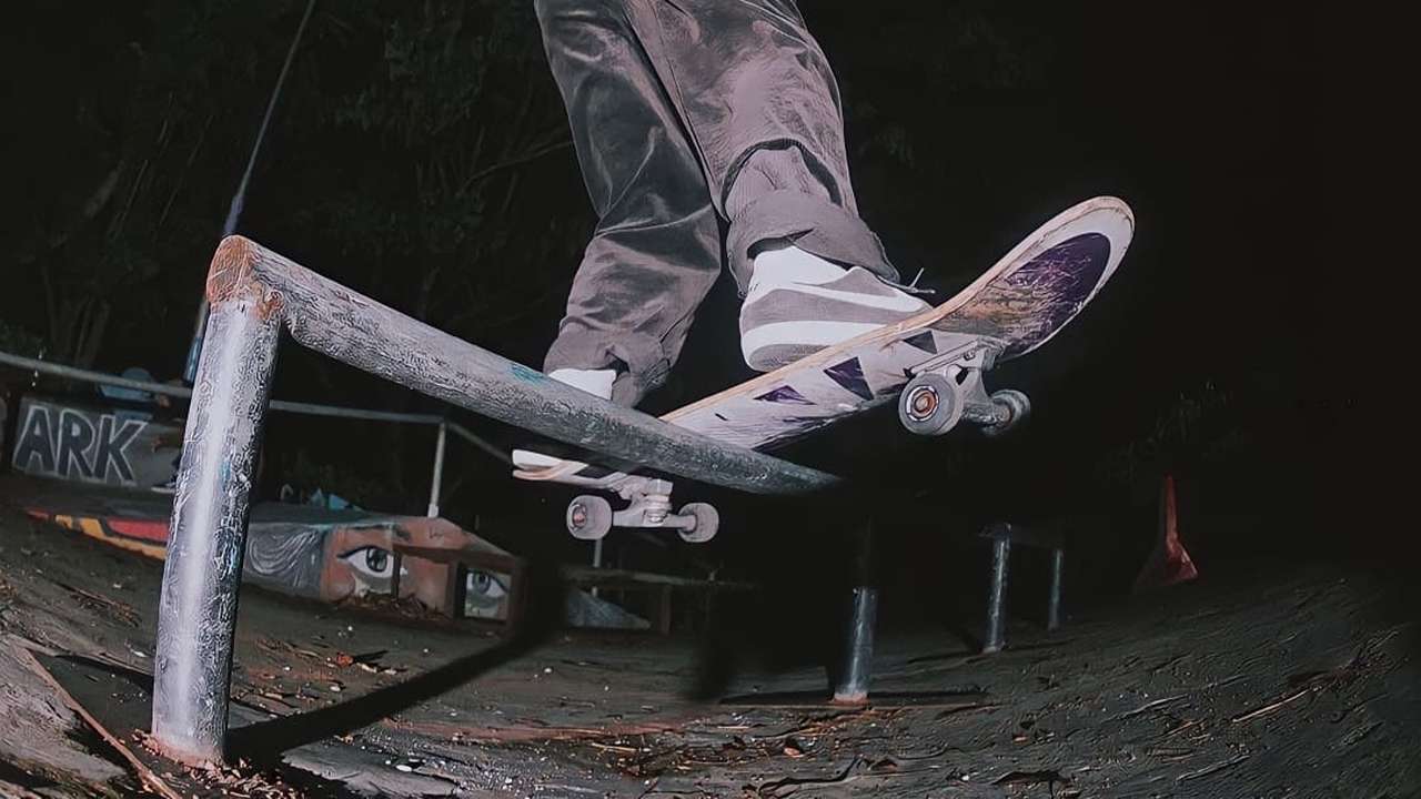 Pemain skate meluncur di tiang slide dengan papan bagian tengah skateboard/Foto: Trenggalek Skateboarding