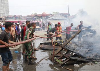 TNI, Petugas Damkar dan masyarakat saat berupaya memadamkan api yang menghanguskan 12 unit rumah, Kamis (28/4).