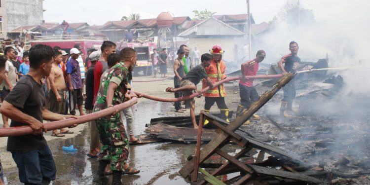 TNI, Petugas Damkar dan masyarakat saat berupaya memadamkan api yang menghanguskan 12 unit rumah, Kamis (28/4).