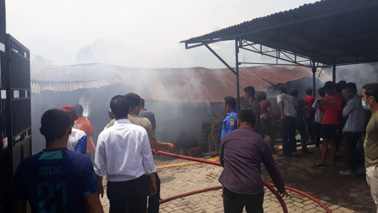 Petugas Damkar dibantu warga saat berupaya memadamkan kobaran api yang menghanguskan gudang dan dapur RM. Riko Sidikalang, Rabu (18/5).