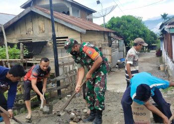 Babinsa Posramil Bukit Tusam, Sertu Basri Pohan ersama warga saat perbaiki jalan rusak, Senin (6/6).