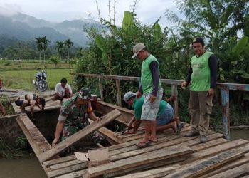 Posramil Lawe Bulan jajaran Kodim 0108/ Agara, Kopda Nelson Sihombing bersama rekan Babinsa dan warga saat perbaiki jembatan penghubung Desa, Jumat (10/6).