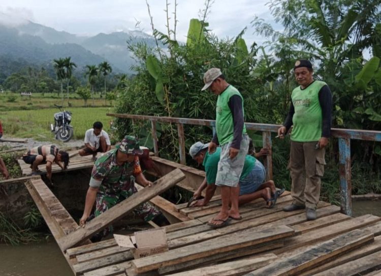 Posramil Lawe Bulan jajaran Kodim 0108/ Agara, Kopda Nelson Sihombing bersama rekan Babinsa dan warga saat perbaiki jembatan penghubung Desa, Jumat (10/6).