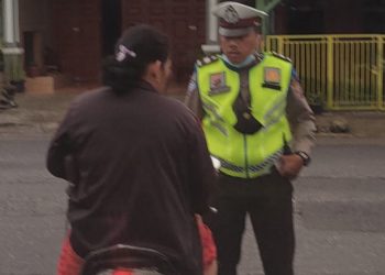 Aiptu Niko Pardosi Personil Satlantas Polres Dairi saat mengamankan seorang pengendara yang tidak menggunakan helm,di persimpangan Jalan Ahmad Yani - Kota Sidikalang, Rabu(5/6).