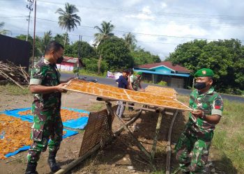 Sertu Daniel Hutagalung bersama rekan Babinsa Posramil Babul Makmur saat komsos bantu jemur kerupuk, Jumat (24/6).
