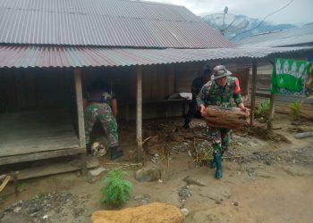 Personil Babinsa Posramil Darul Hasanah saat membersihkan materail berupa puing kayu, lumpur dan batu pasca banjir luapan sungai, Jumat (24/6).
