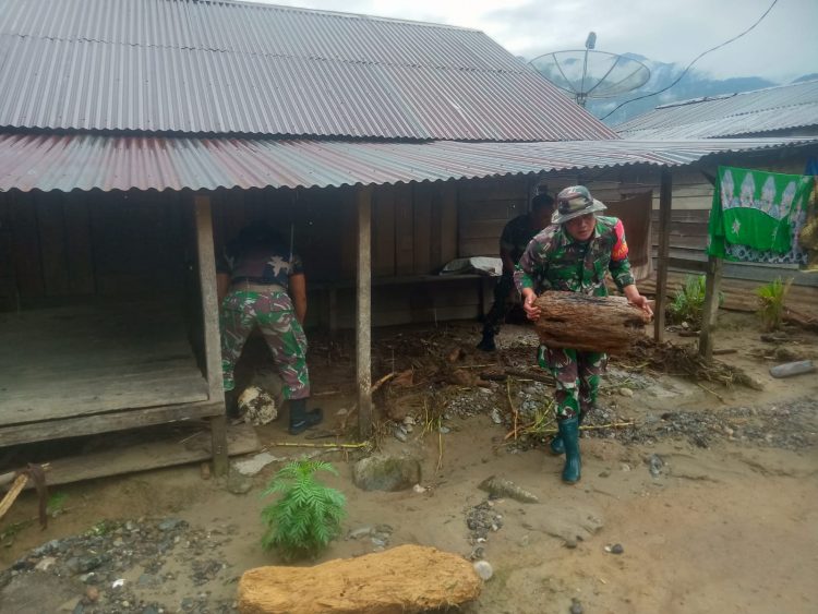Personil Babinsa Posramil Darul Hasanah saat membersihkan materail berupa puing kayu, lumpur dan batu pasca banjir luapan sungai, Jumat (24/6).