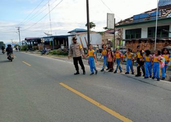 Personil Polres Dairi saat menyeberangkan siswa/i, Jumat (19/8).