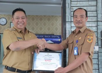 Bupati Dairi, Dr. Eddy Berutu saat memberikan penghargaan kepada Kadis Dukcapil Dairi, Dedy Situmorang atas kinerja, Senin (3/10).