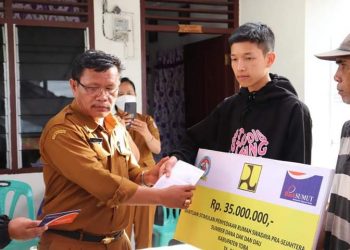 Kepala Dinas Perumahan dan Kawasan Permukiman (Perkim), Tagor Siburian saat menyerahkan bantuan kepada 20 kepala keluarga di Desa Patane I, Kecamatan Porsea, Kabupaten Toba - Sumatera Utara, Senin (3/10).