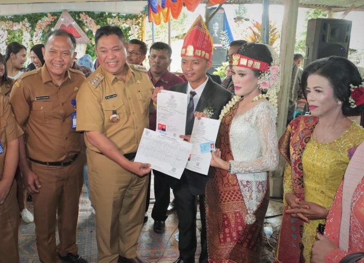 Bupati Dairi, Dr. Eddy Berutu bersama Kadis Dukcapil Dairi, Deddy Situmorang saat serahkan Aminduk kepada kedua mempelai, Senin (3/10).