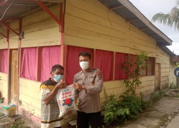 Bhabinkamtibmas 
Polsek Porsea, AIPDA. Joko Sitorus dan Briptu. Herwanto Siagian saat membagikan bansos sembako, Jumat (21/10).
