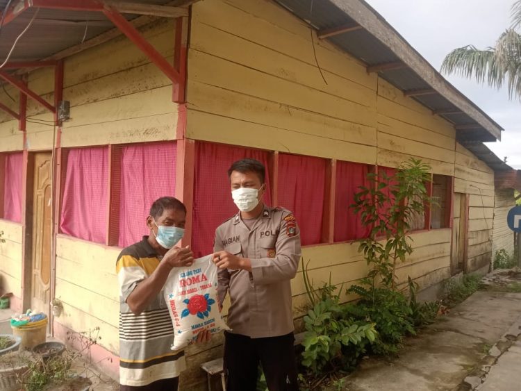 Bhabinkamtibmas 
Polsek Porsea, AIPDA. Joko Sitorus dan Briptu. Herwanto Siagian saat membagikan bansos sembako, Jumat (21/10).
