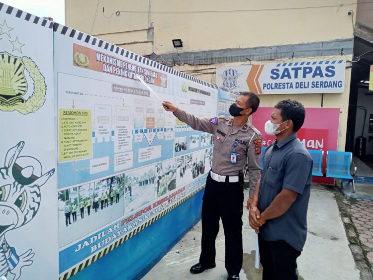 Bripka Riko Sitepu, petugas Pelayanan Suran Izin Mengemudi Polresta Deliserdang saat memberikan bimbel gratis kepada pemohon, Sabtu (19/11).