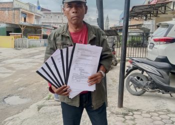 Maringan Napitupulu saat menunjukkan berkas aduanya ke Ombusman RI, Selasa (3/1).