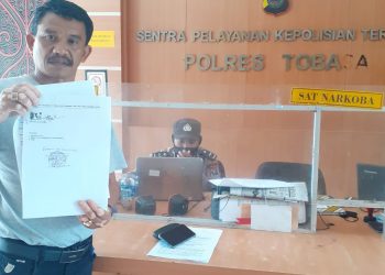 Djonggi Napitupulu yang juga keluarga Pelapor Jhon Ferry Simanjutak menunjukkan bukti laporan, Selasa (17/1). 