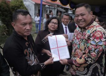 Bupati Dairi, Eddy Begitu saat menyerahkan sertifikat tanah milik GMI Lae Mbulan, Minggu (12/2).