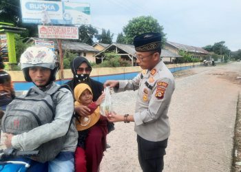 Kapolsek Belitang II, AKP. Aston L Sinaga SH saat berikan takjil kepada warga pengguna jalan, Sabtu (25/3).