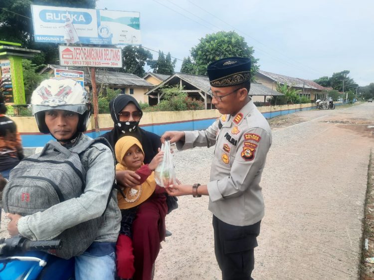 Kapolsek Belitang II, AKP. Aston L Sinaga SH saat berikan takjil kepada warga pengguna jalan, Sabtu (25/3).