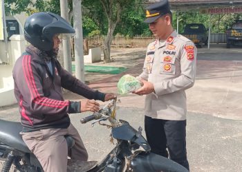 Kapolsek Semendawai Suku III, IPTU. L.A.E Tambunan saat berikan takjil kepada warga, Jumat (31/3).