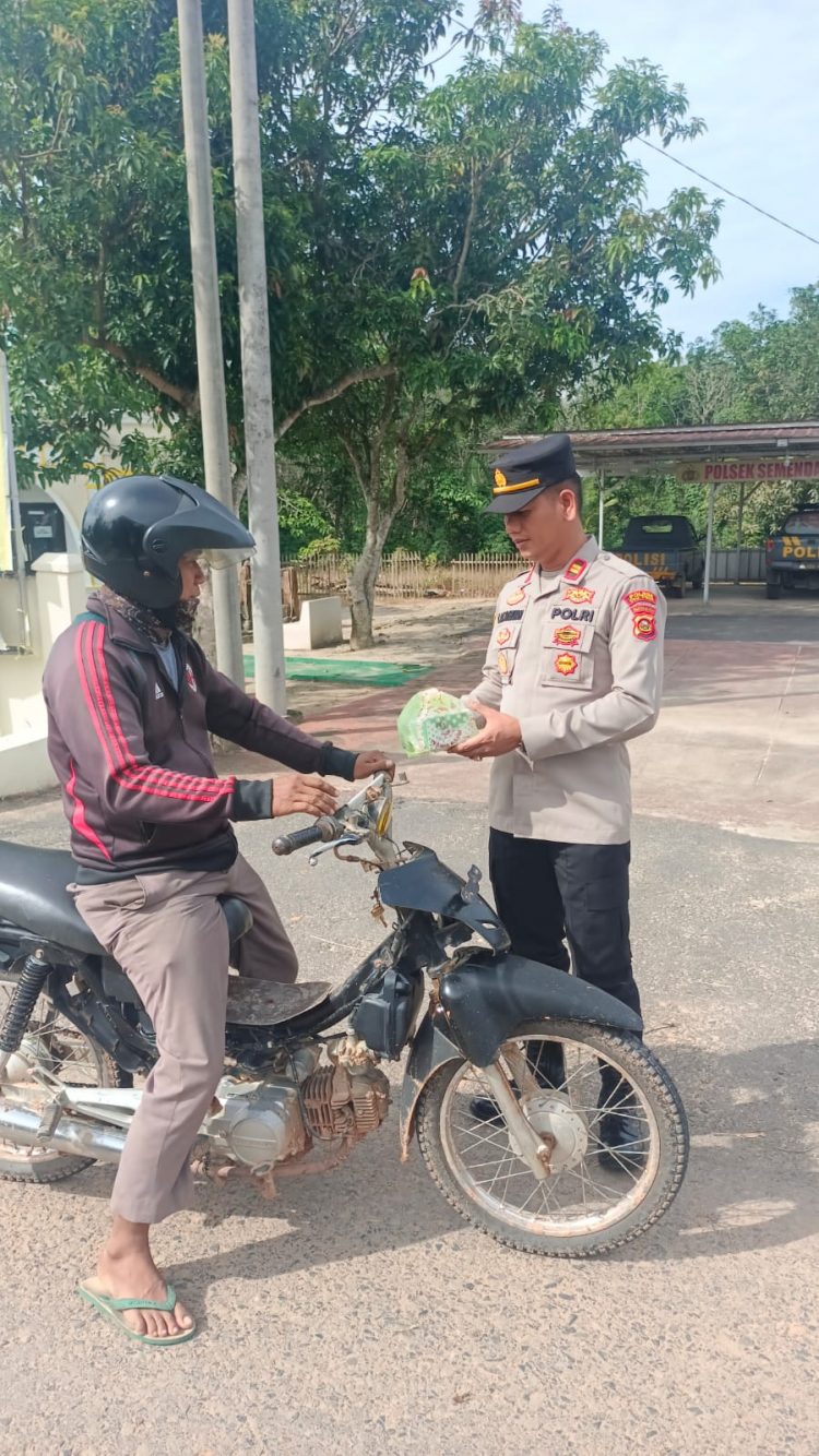 Kapolsek Semendawai Suku III, IPTU. L.A.E Tambunan saat berikan takjil kepada warga, Jumat (31/3).