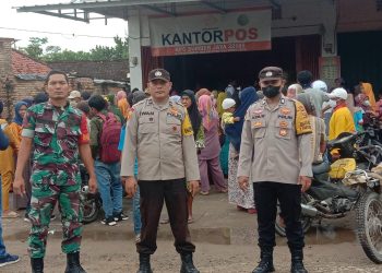 Personil Polsek Belitang II dan Koramil Belitang II saat PAM pembagian bantuan beras di kantor Pos, Senin (10/4).