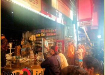 Puluhan warga saat membantu padamkan api dan pindahkan barang dagang milik Toko Ramos yang terbakar, Sabtu malam (18/6).