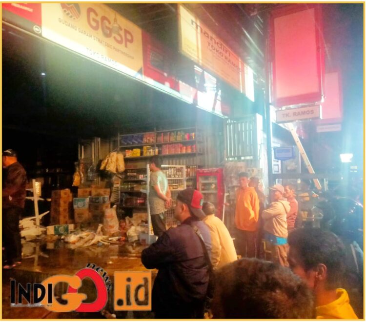 Puluhan warga saat membantu padamkan api dan pindahkan barang dagang milik Toko Ramos yang terbakar, Sabtu malam (18/6).