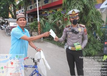 Kasat Lantas AKP H.W Siahaan SH saat bagikan masker kepada seorang warga