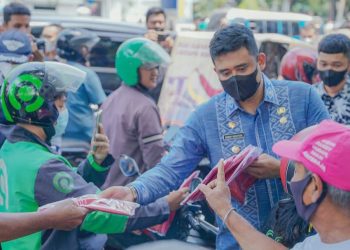 Bobby Nasution, Wali Kota Medan bersama unsur Forkopimda membagikan Bendera Merah Putih kepada masyarakat melintas di Jalan Balai Kota Medan. (Foto Ist)