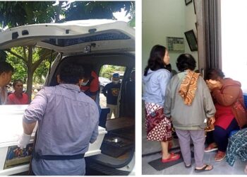 Kanit Reskrim Polsek Siantar Martoba IPDA Sahat Sinaga SH bantu angkat peti jenajah korban kedalam ambulance dan isteri korban Lenni Verawati Tampubolon tak henti henitnya menangis diruangan jenajah