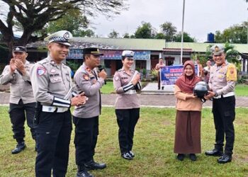 Kasat Lantas Polres Simalungun AKP Jonny F Sinaga SH memberikan helm kepada seorang pelajar saat sosialisasi Ops Keselamatan Toba Tahun 2025