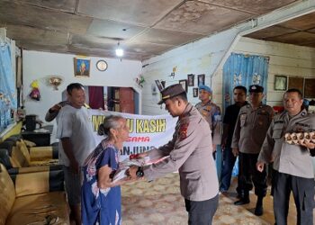 Kapolsek Datuk Bandar AKP John Herbert Turnip SE saat berikan bantuan kepada salah satu warga yang membutuhkan