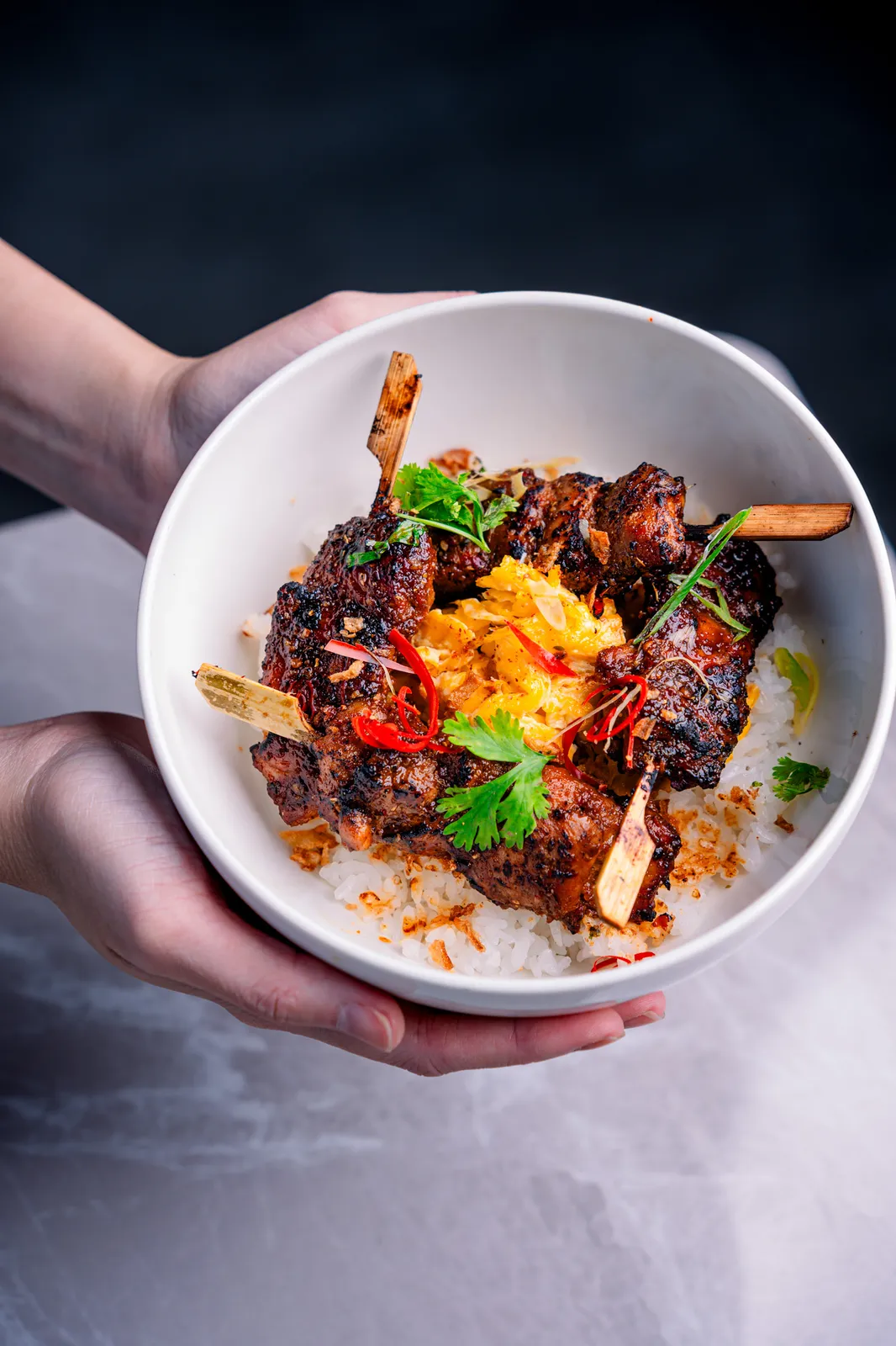 Chicken satay bowl served by hand