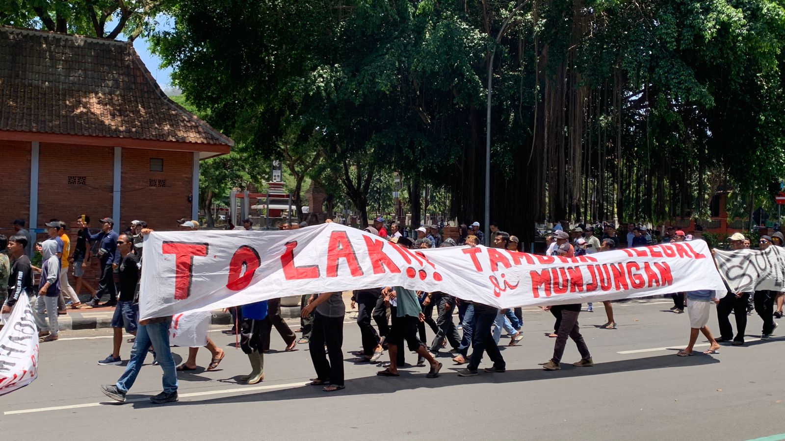 baner protes dibentangkan warga munjungan saat unjuk rasa