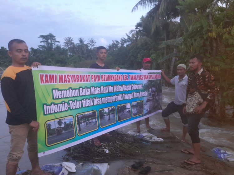 Warga Paya Beurandang membentangkan spanduk permintaan kepada Pemerintah agar melakukan perbaikan terhadap tanggul