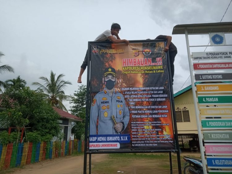 Personel Polsek Sawang memasang spanduk sosialisasi pencegahan kebakaran hutan dan lahan (karhutla) di Gampong Tanjong Keumala