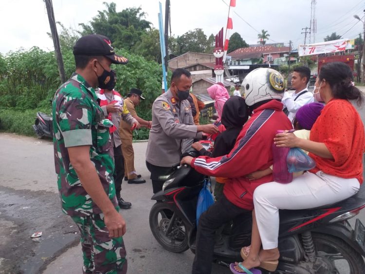 Kapolsek Sidikalang Kota AKP Sukanto Berutu, SH membagikan Bendera Merah Putih kepada masyarakat yang mengendarai kenderaan di jalan Sidikalang - Tigalingga KM 2